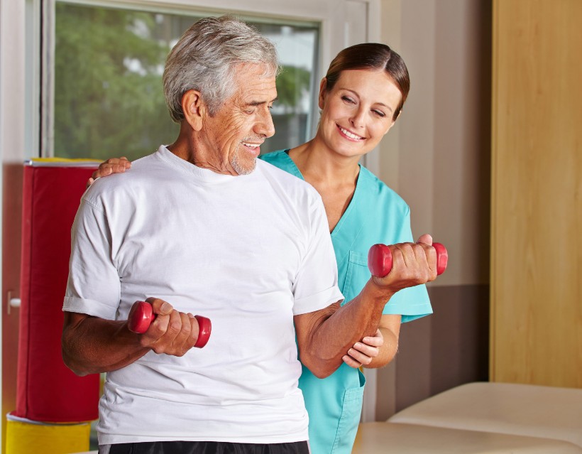 healthcare worker assisting a senior resident with physical therapy
