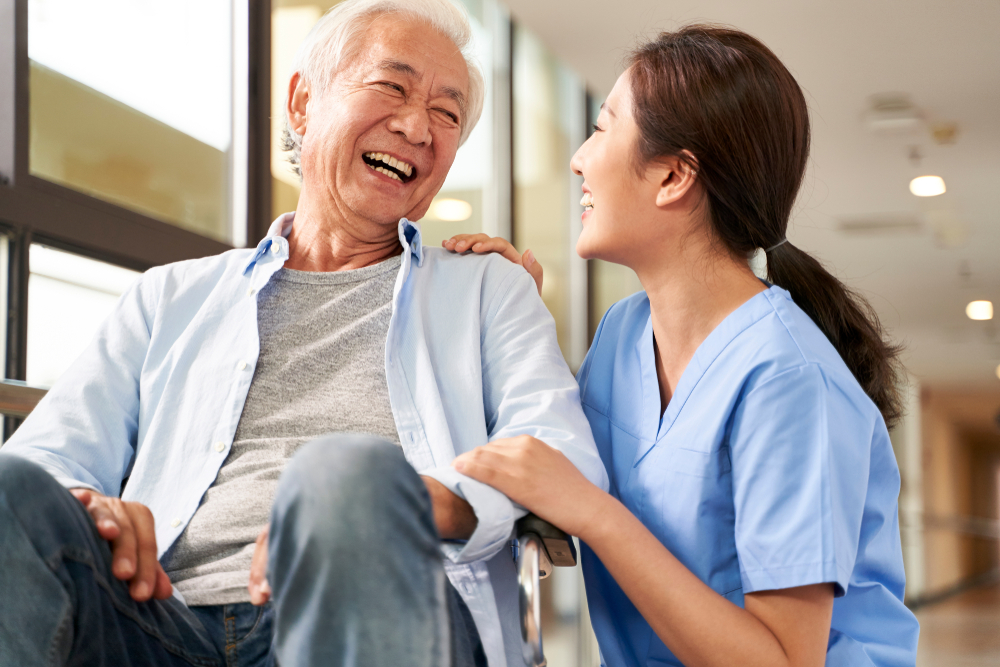 Senior man in a wheelchair laughing with a nurse