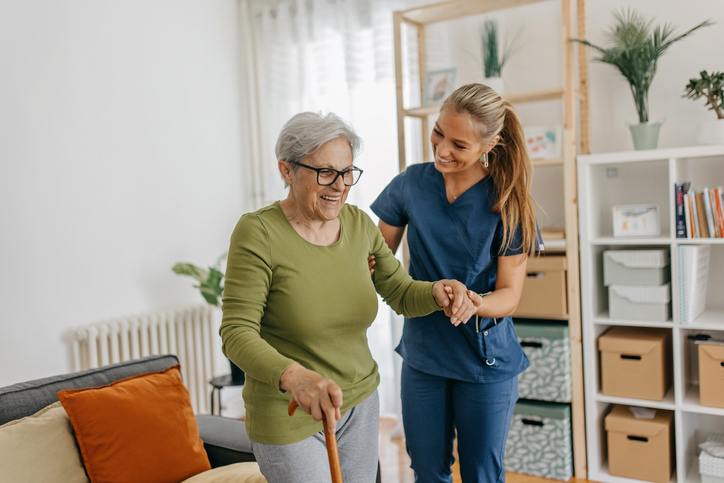 Caregiver assisting an older woman at a senior community, or nursing home