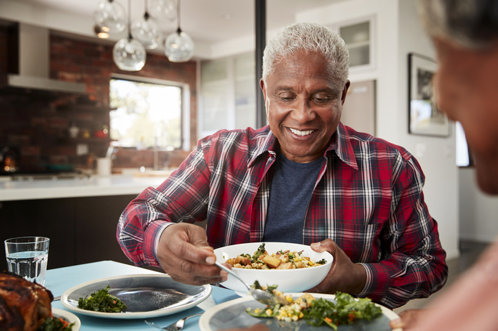 Older man eating food at a table.