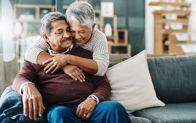 Senior woman hugging senior man on a couch