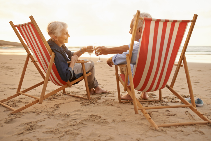 Senior couple relaxing on the beach with glasses of wine