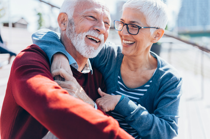 Two older adults embracing and smiling in the Florida sun.