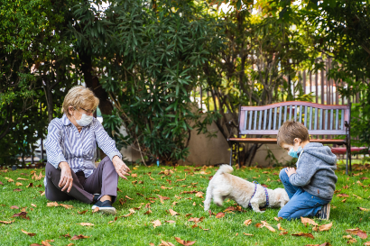 senior woman and her grandchild playing with a dog outside