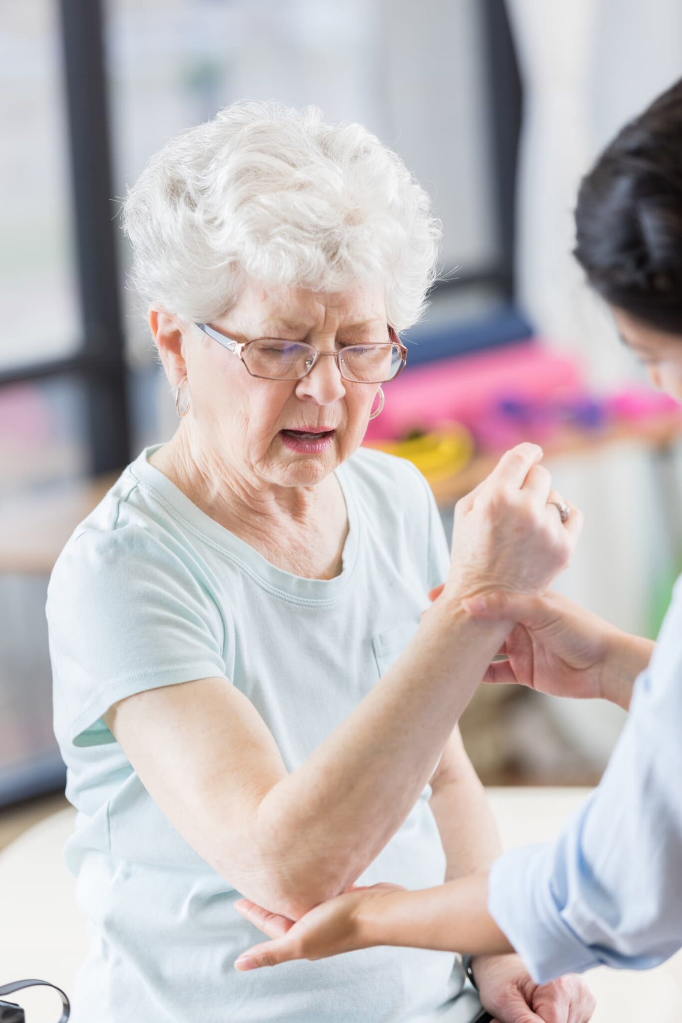 Older woman working on arm range of motion with therapist.